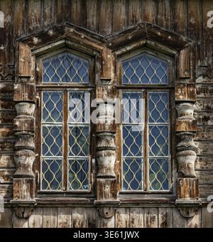Holzfenster mit Metallstangen in einem alten Holzhaus Stockfoto
