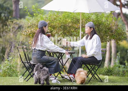Ein koreanischer Mann und eine Japanerin, beide im Alter von 30 Jahren und ein verheiratetes Paar, genießen in einem stilvollen Café im Herbst einen Brunch mit drei Hunden Stockfoto