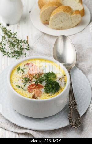 Lachs cremige Suppe mit Gemüse - Kartoffeln, Karotten, Tomaten und Brokkoli in einer weißen Schüssel auf hellem Holztisch Stockfoto