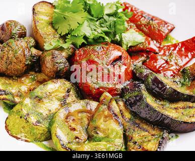 Speisen, Eine lebendige Auswahl an gegrilltem Gemüse, einschließlich Zucchini, Auberginen, Pilzen und roten Paprika, garniert mit frischem Koriander, hervorheben Stockfoto