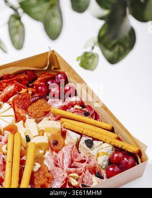 Essen, Eine schön gestaltete Wurstplatte bietet eine Auswahl an Wurstwaren, Käse, frischem Obst und Nüssen. Die lebendigen Farben sorgen für einen Innenraum Stockfoto