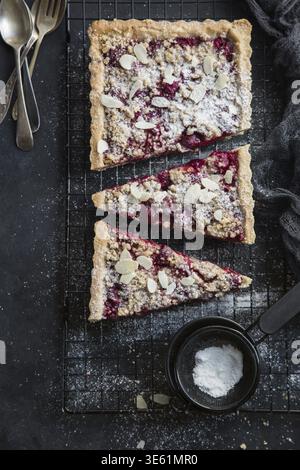 Essen, Kirsch- und Mandel-Streuseltorte, schwarzer Hintergrund, Blick von oben Stockfoto