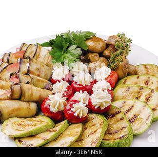 Speisen, Eine lebendige Auswahl an gegrillten Zucchini, Auberginen-Brötchen, gefüllten Kirschtomaten mit cremiger Füllung und sautierten Pilzen auf einem Rind Stockfoto
