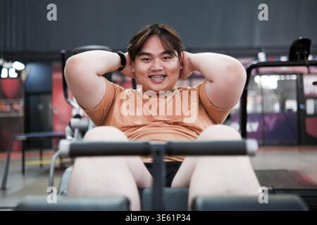 Übergewichtiger Mann, der Sit-ups während eines Workouts im Fitnessstudio macht. Konzentrieren Sie sich auf Gewichtsverlust, Kernkraft und gesunde Lebensweise. Das Konzept der Fitness Challengeng Stockfoto