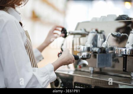 Ein Barista oder Café-Mitarbeiter, der eine Espressomaschine verwendet, um Kaffee in einem Café zuzubereiten. Die Szene zeigt das Engagement, die Präzision und die Kundenorientierung Stockfoto