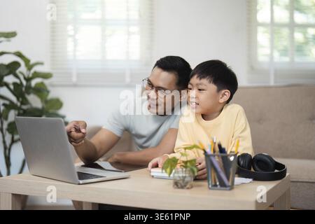 Ein Vater und Sohn teilen ein unterhaltsames Homeschooling-Erlebnis, beschäftigen sich mit dem Material und genießen ihre Zeit zu Hause Stockfoto