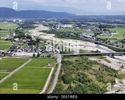 Eine ländliche Gegend mit einem Fluss, der durch sie fließt. Der Fluss ist von grünen Feldern und Bäumen umgeben Stockfoto