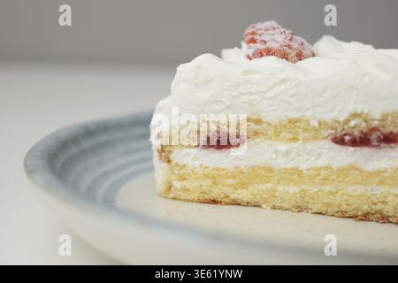 Ein kleiner japanischer Erdbeer-Shortcake auf einem stilvollen japanischen Teller auf einem weißen Tisch Stockfoto