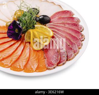 Essen, eine kunstvoll gestaltete Platte zeigt verschiedene Arten von rohem Fisch, einschließlich Lachs und Thunfisch, garniert mit Zitronenscheiben, Oliven und frischen Kräutern Stockfoto