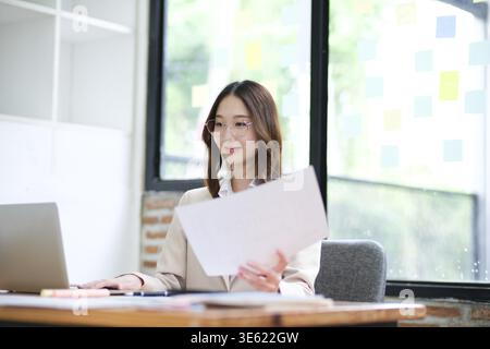 Eine Geschäftsfrau konzentriert sich auf die Analyse von Daten und die Verwaltung von Online-Investitionen. Ihre berufliche Tätigkeit umfasst Finanzen, Buchhaltung und Entscheidungsfindung. Stockfoto