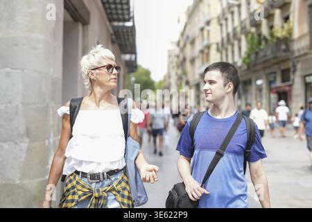 Ein Mann und eine Frau gehen die Straße entlang, der Mann trägt ein blaues Hemd und die Frau ein weißes Hemd Stockfoto
