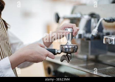 Ein Barista streichelt Kaffeesatz in den Portafilter und zeigt Präzision und Geschick. Die Szene hebt Professionalität und Liebe zum Detail in hervor Stockfoto