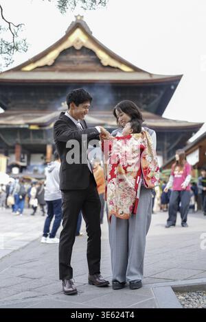Ein Mann und eine Frau stehen vor einem Gebäude, die Frau trägt einen roten Kimono Stockfoto