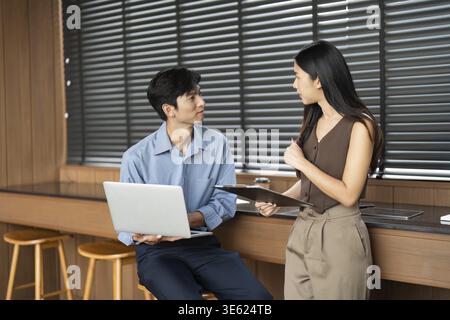 Ein junger Mann und eine junge Frau arbeiten an einem Geschäftsprojekt zusammen und tauschen Erkenntnisse und Strategien in einem modernen Arbeitsbereich aus Stockfoto