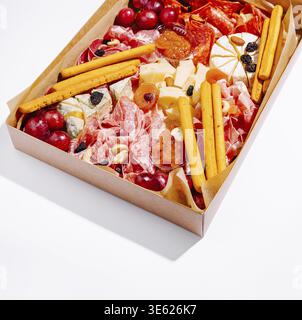 Essen, Eine schön gestaltete Wurstplatte zeigt eine Vielzahl von Wurstwaren, verschiedenen Käsesorten, Trauben, getrockneten Früchten und Brotstäbchen, perfekt für Stockfoto
