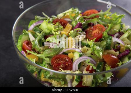 Lebensmittel, Tomaten, Paprika, Gurken, Salat und Salat aus roten Zwiebeln in einer Glasschale, selektiver Fokus Stockfoto