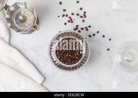 Eine Kaffeekanne und ein Glas geröstete Kaffeebohnen. Blick von oben auf den Marmortisch Stockfoto