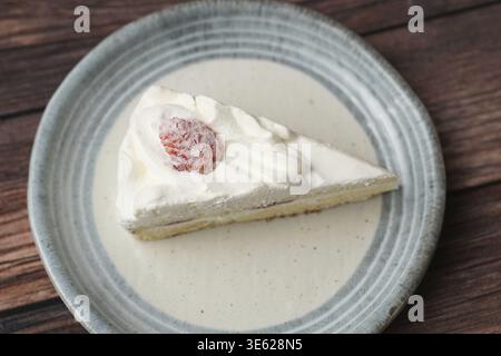 Ein kleiner japanischer Erdbeer-Shortcake auf einem stilvollen japanischen Teller auf einer braunen Holzterrasse Stockfoto