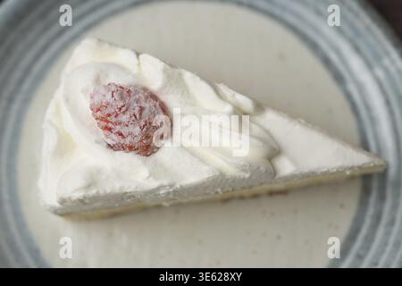 Ein kleiner japanischer Erdbeer-Shortcake auf einem stilvollen japanischen Teller auf einer braunen Holzterrasse Stockfoto