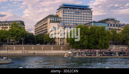 Paris, Frankreich - 08 04 2025: Ein großes Doppeldeckerboot fährt die seine im Zentrum von Paris. Der Hintergrund zeigt eine Mischung aus historischem H Stockfoto