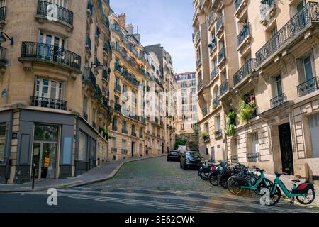 Paris, Frankreich - 08 04 2023: Ein großer Blick auf eine malerische gewundene Straße im 18. Arrondissement von Paris. Die Szene zeigt hohe Kalksteinresidenz Stockfoto