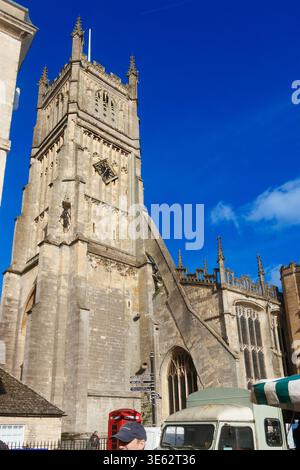 Die Kirche St. Johannes des Täufers mit Marktständen im Freien am Cirencester Market Place unter einem klaren blauen Himmel Stockfoto