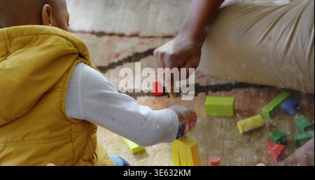 Sitzendes Kind mit gelber Weste, Holzblöcke auf gemustertem Teppich, Kopierraum Stockfoto
