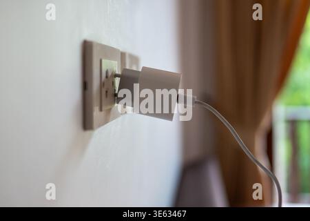 Unpraktische Hotelsteckdose in Asien, Smartphone-Ladegerät fällt aus der Steckdose und lädt nicht auf. Stockfoto