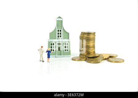 Ein Paar Zieht Einen Hauskauf In Betracht, Mit Stapeln Von Münzen, Die Hypothekeneinsparungen Und Investitionen Darstellen Stockfoto
