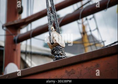 Nahaufnahme eines antiken hölzernen Flaschenblocks und Seile auf einem Segelschiff in Emden. Konzentrieren Sie sich auf die verwitterte Textur der Holz- und Faserseile Stockfoto