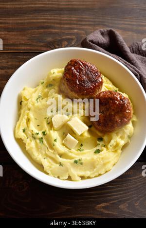 Kartoffelpüree mit Hackschnitzel in einer Schüssel auf Holztisch. Gesunde Komfortkost. Nahansicht Stockfoto