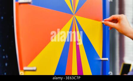 Das Mädchen dreht bunte Streifen auf dem Rad. Stockfoto