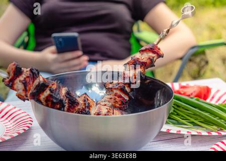 Picknick in der Natur, gekochter Grill und Gemüse mit Kräutern auf dem Tisch. Stockfoto