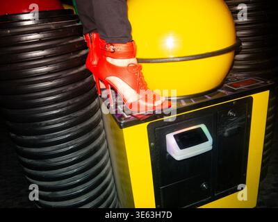 Zwei Personen stehen auf einem Kasino-Boden mit High Heels und Stiefeln, umgeben von Münzen und Tickets. Stockfoto