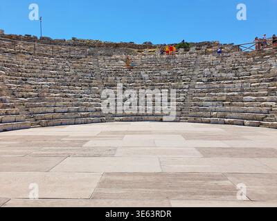 Antike Steinfasstheater mit mehrstufigen Sitzgelegenheiten unter klarem blauem Himmel. Die archäologische Stätte verfügt über verwitterte Steintreppen, die in einem angeordnet sind Stockfoto
