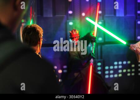 Das Bild zeigt eine Indoor-Szene mit einer Figur, die Darth Maul aus Star Wars ähnelt, erkennbar an roter und schwarzer Gesichtsfarbe, klein Stockfoto