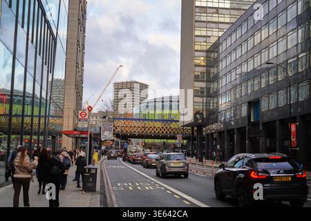 Eine geschäftige urbane Straßenszene in London, Großbritannien, mit modernen Hochhäusern aus Glas und Stahl, die beide Seiten der Straße säumen. Fußgänger gehen entlang Stockfoto