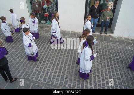 Kinder, die in einer Prozession in der Semana Santa (Heilige Woche) in Mijas, Andalusien, Spanien laufen Stockfoto