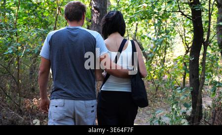 Glückliches Paar, das auf dem Weg im Sommerwald spaziert. Romantische Paare auf dem Weg durch wilde Wälder. Liebhaber verbringen Zeit zusammen in der Natur. Konzept Stockfoto