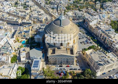 Aus der Vogelperspektive der Mosta Rotunde in Mosta, Malta, mit der massiven runden Kirche und Kuppel, umgeben von dichten Kalksteinbauten in hellen Farben Stockfoto