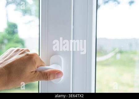 Das Kunststofffenster wird mit einem weißen Griff geöffnet, hochwertige Hardware, Einrichtung für komfortable Lüftung, Schalldämmung, Anti-Draft-Funktionen und Business i Stockfoto