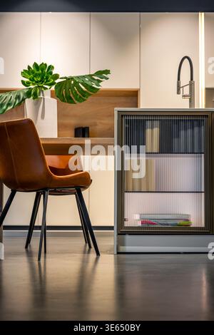 Moderne Küche mit Ledersessel. Minimalistischer Essbereich mit geripptem Schrank. Stockfoto