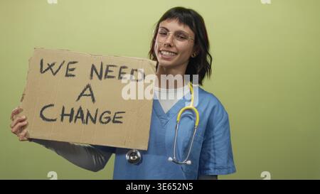 Eine Krankenschwester in blauem Gewand hält ein Pappschild mit der Aufschrift, wir brauchen einen Atelierwechsel, hoffen, dass sich der Aktivismus reformieren lässt. Stockfoto
