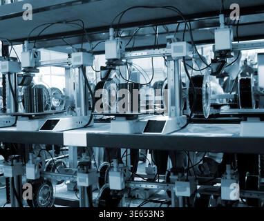 Viele 3D-Drucker drucken Objekte. 3D-Drucker, die eine Form aus geschmolzenem Kunststoff erzeugen, der aus dem Extruder fließt. Nahaufnahme des 3D-Druckers. Arbeitender 3D-Drucker druckt Objekt aus geschmolzenem schwarzem Kunststoff Stockfoto