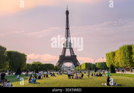 Paris, Frankreich - 08 05 2023: Weitwinkelblick auf den berühmten Eiffelturm während der goldenen Stunde. Das Bild zeigt Dutzende von Menschen, die einen sitzen Stockfoto