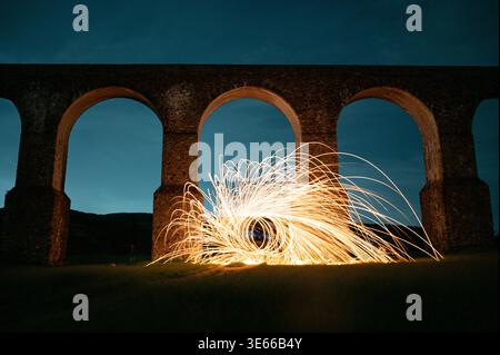 Helles Gemälde aus Stahlwolle bei Nacht vor historischen Steinbögen in Mexiko Stockfoto