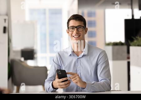 Porträt eines selbstbewussten Mannes mit Smartphone im Büro Stockfoto