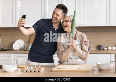 Frau und Sohn posieren für Selfie beim Kochen in der Küche Stockfoto