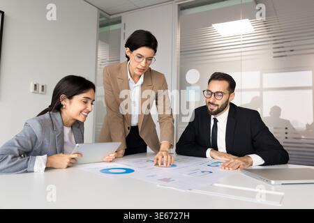 Verschiedene Teams, die Geschäftsdiagramme während der Besprechung im Vorstandssitz analysieren Stockfoto