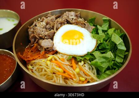 Traditionelles koreanisches Bibimbap in goldener Messingschale, gemischter Reis mit Rindfleisch-Bulogogi, gebratenes Ei und frisches Gemüse, authentische K-Food-Küche Stockfoto